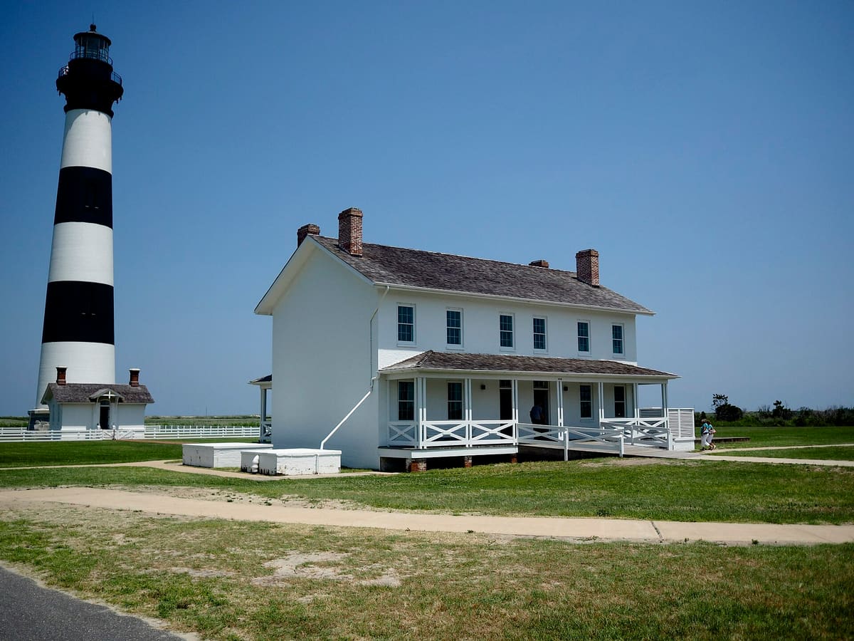 The white two storey keepers' quarters with the lighthouse standing beyond it