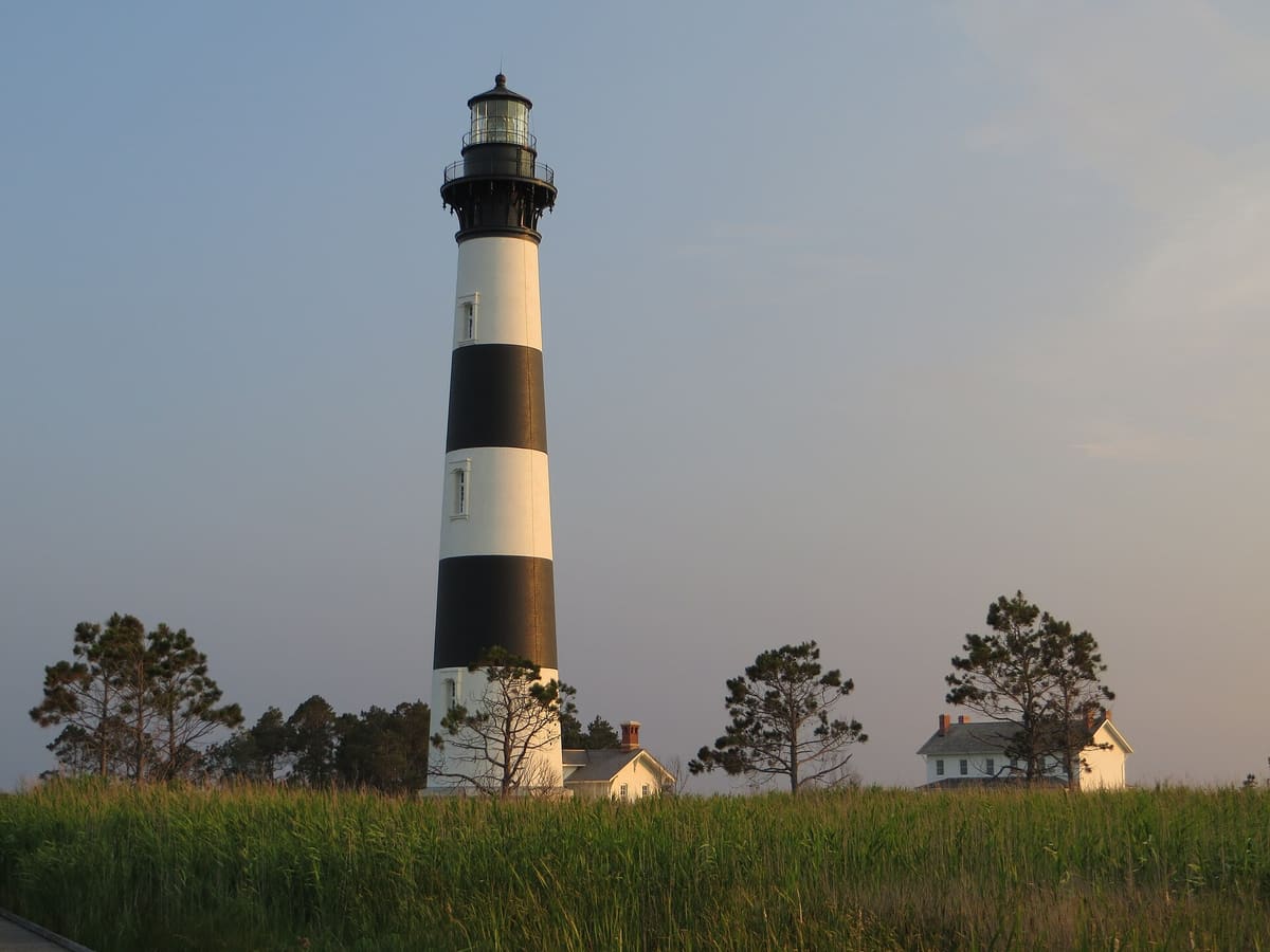 The full black and white banded tower rising above the treeline against blue sky