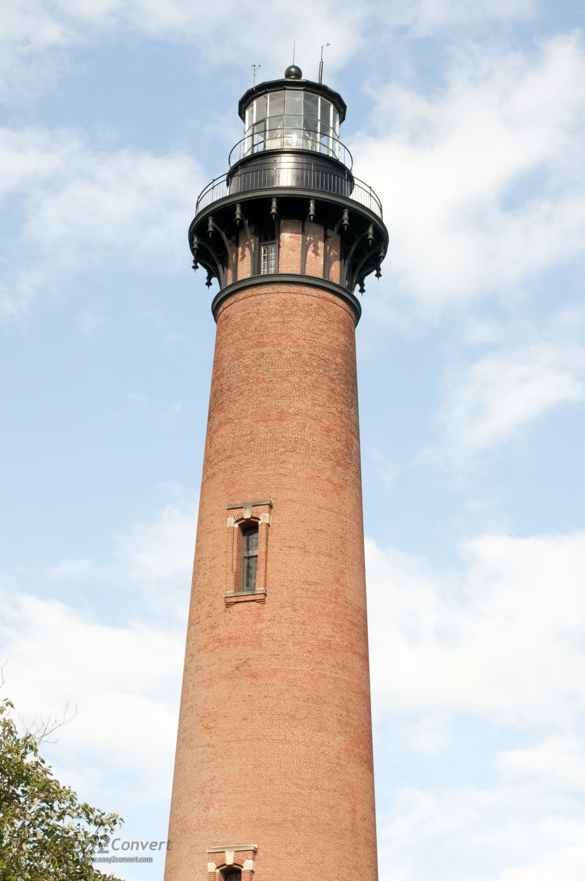 The unpainted red brick of the tower against a clear blue sky