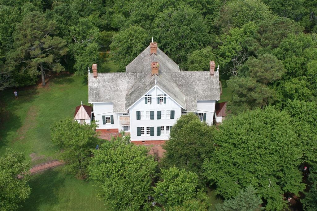 The white timber keepers' duplex with its steep roof, surrounded by trees