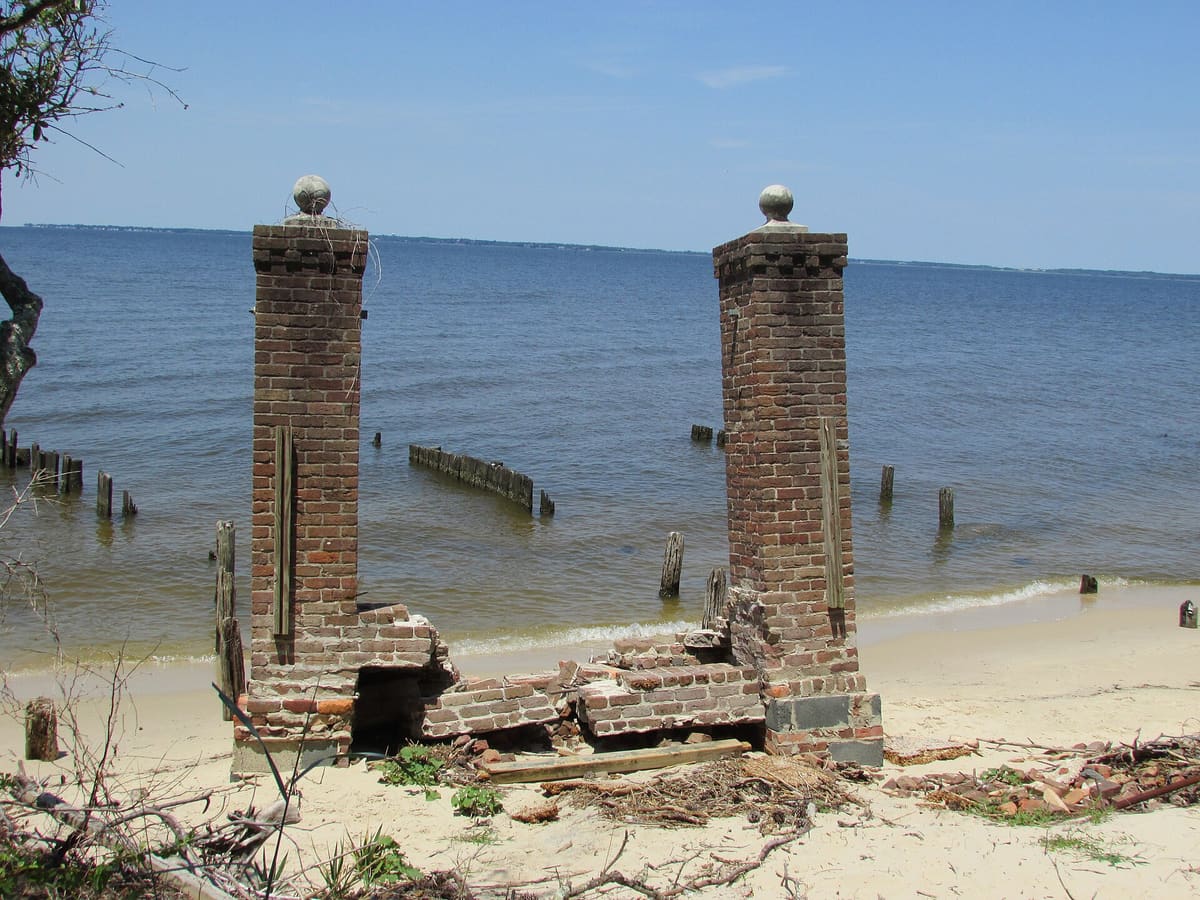 Two brick pillars from a ruined pier standing on the eroded sound shoreline at the Elizabethan Gardens