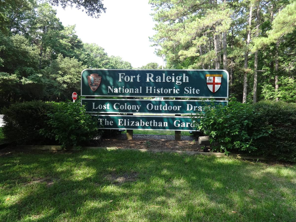 The brown park entrance sign for Fort Raleigh National Historic Site listing the Lost Colony outdoor drama and the Elizabethan Gardens