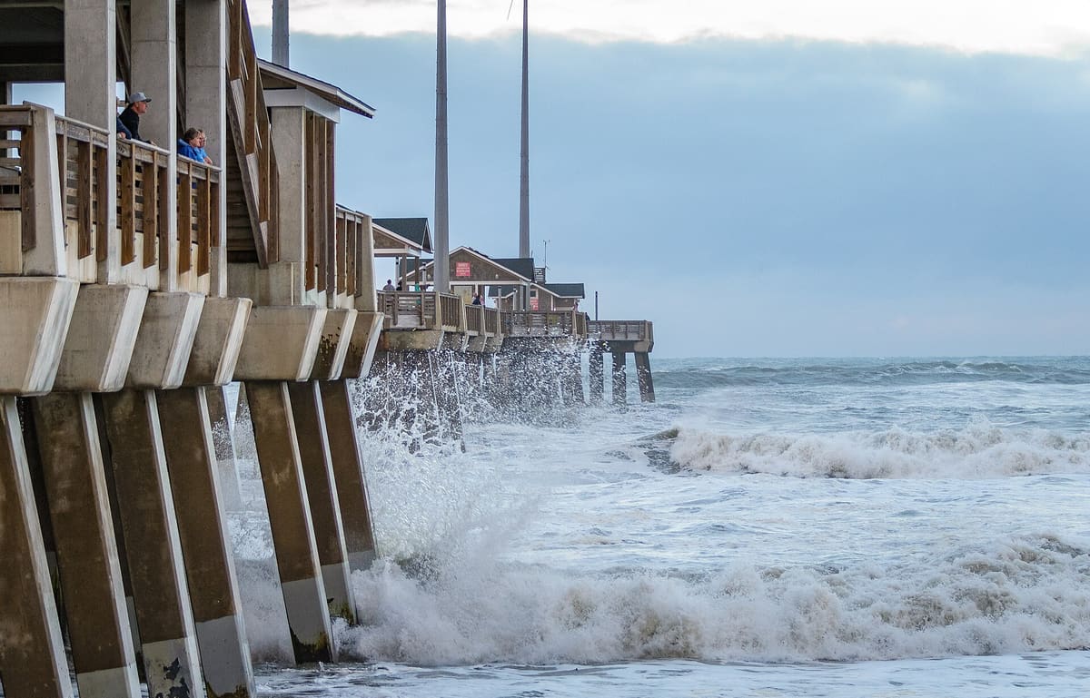Waves breaking hard against the concrete pilings under the pier deck