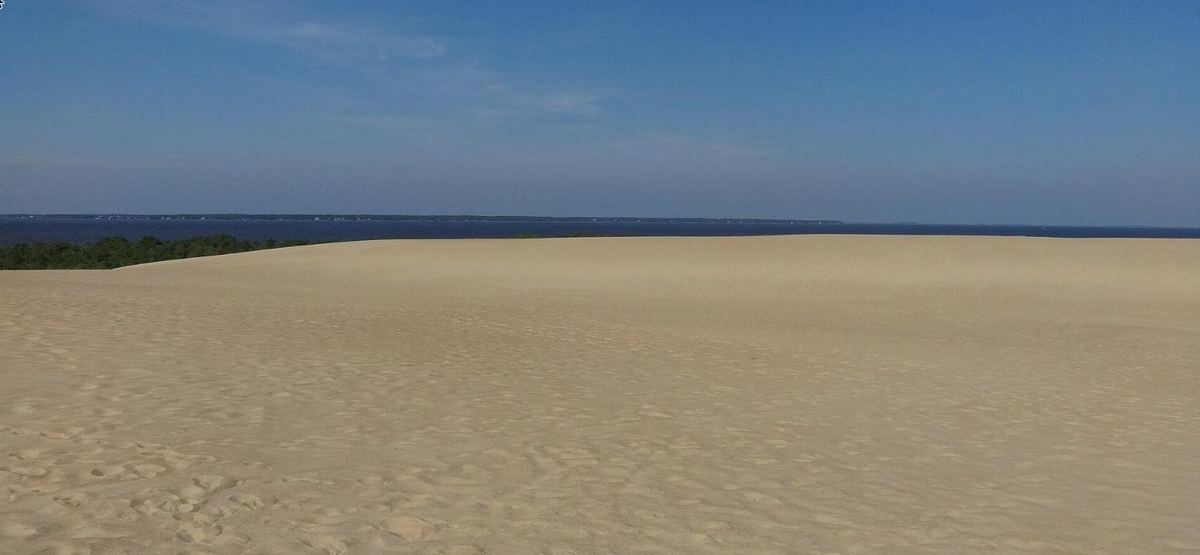 The crest of the dune with the flat blue water of Roanoke Sound stretching out behind it