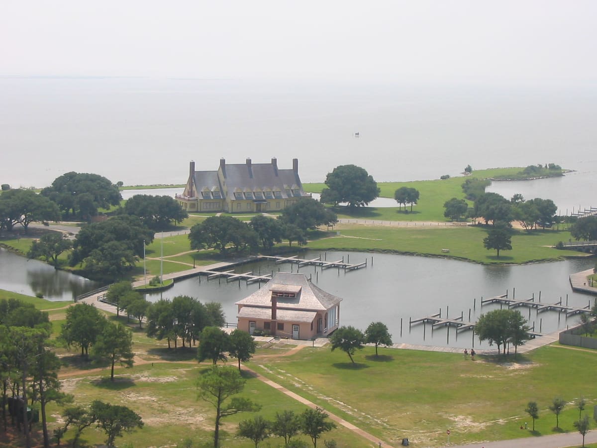 The yellow Whalehead house with its copper roof seen across the lawn and boat basin