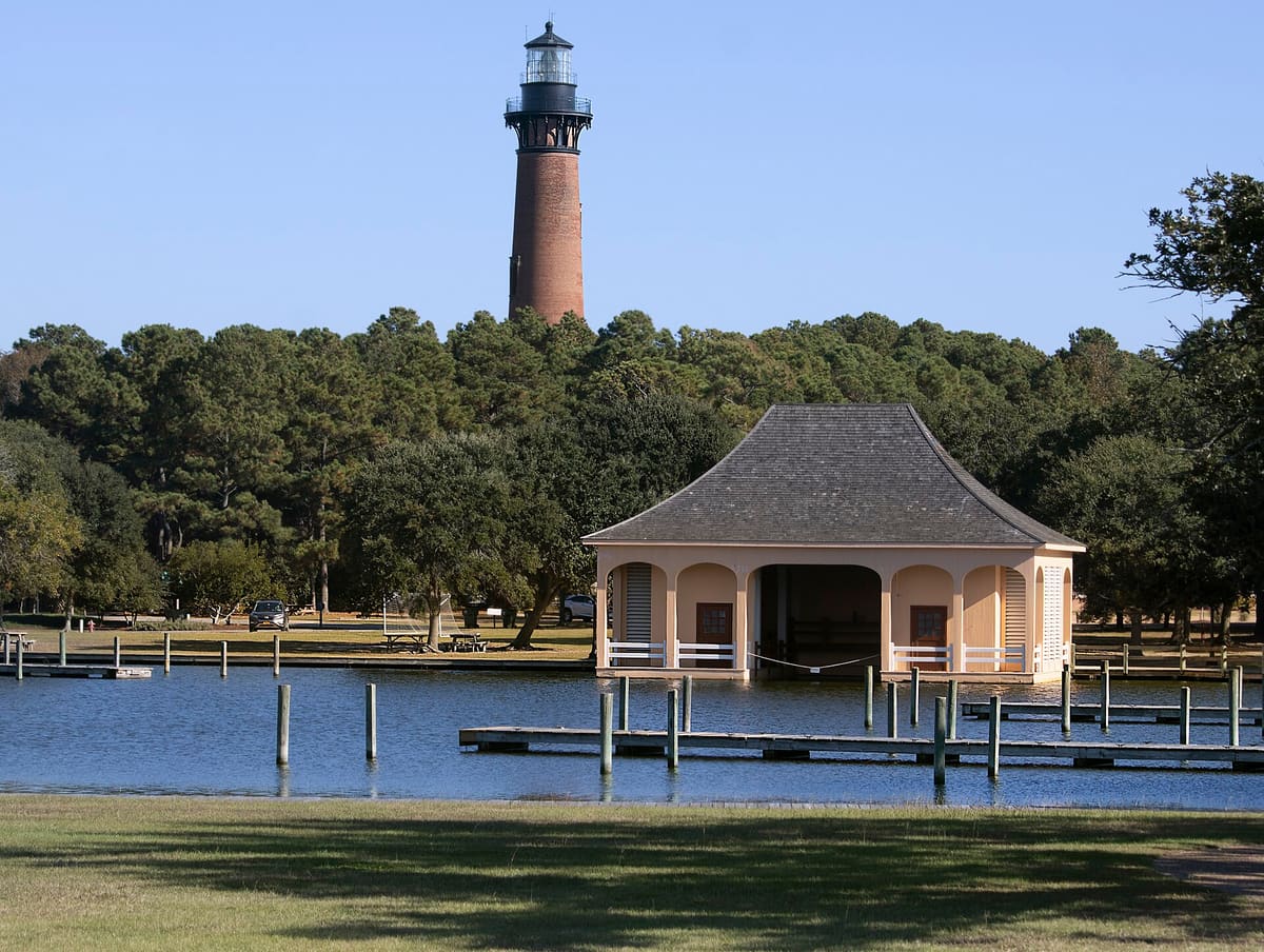 The restored Whalehead boathouse on the sound with the Currituck Beach Lighthouse rising behind it