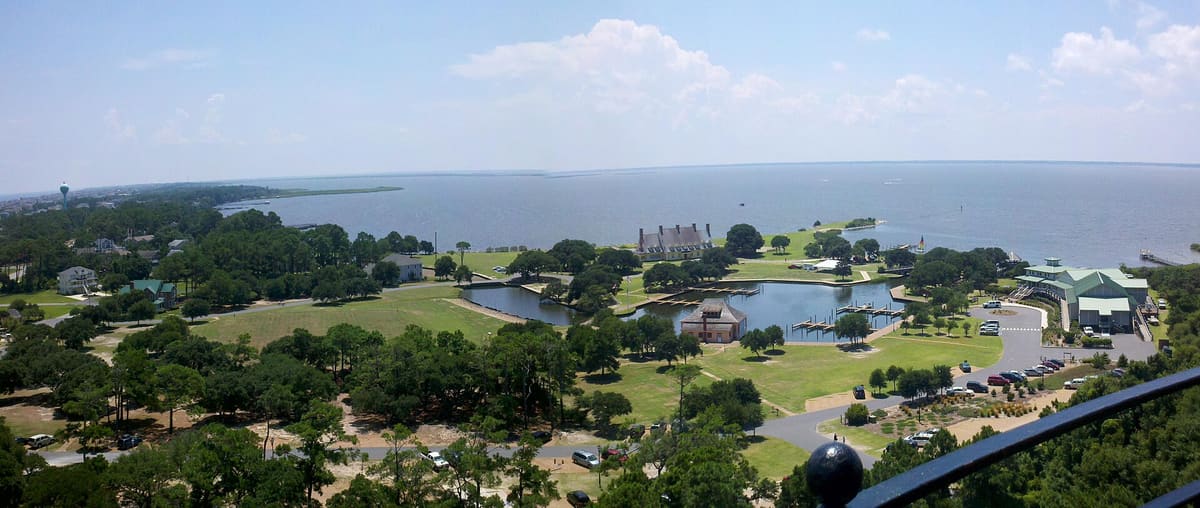 A wide view across Historic Corolla Park with the Whalehead house, the boat basin and the ocean beyond