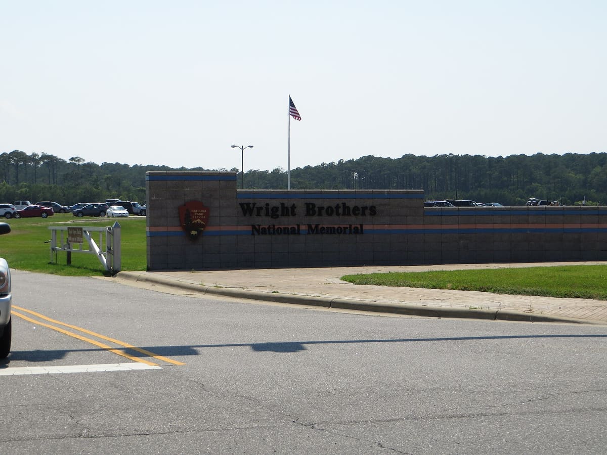 The entrance sign at the memorial with the park road behind it