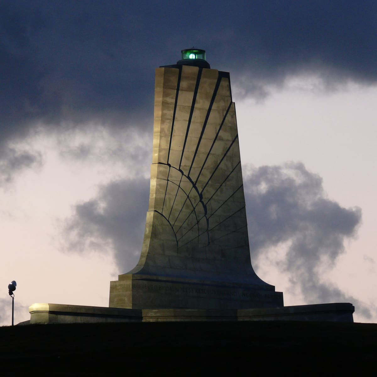 The granite monument standing on top of Kill Devil Hill against a bright sky