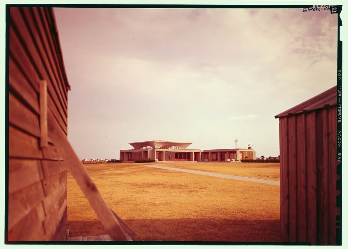 The low modernist visitor center building seen across the grounds in warm light